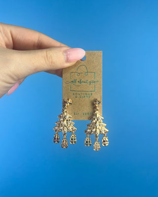 Shop the Christmas Tree Earrings at All About You Boutique! Festive gold-tone holiday earrings with pearl accents, sparkling stars, and dangling gift charms.