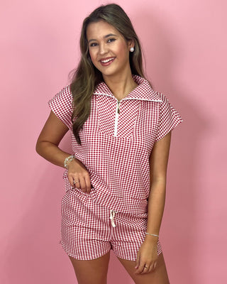 Woman wearing a red and white checkered outfit on a pink background