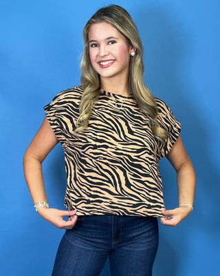 A woman modeling a short-sleeve tiger-print top and dark blue cropped jeans