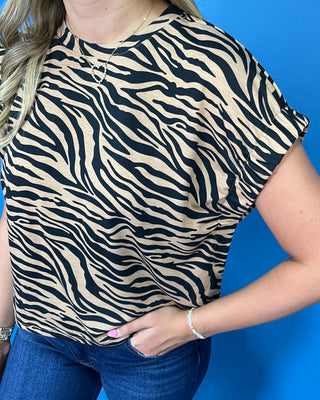 A woman modeling a short-sleeve tiger-print top and dark blue cropped jeans