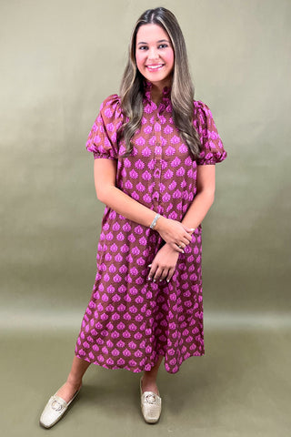 Woman wearing a pink patterned dress against a green background