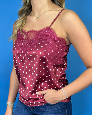 Burgundy satin polka dot camisole with delicate lace trim, thin straps, and a feminine relaxed fit.