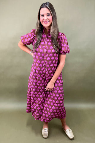 Woman wearing a pink patterned dress against a plain background