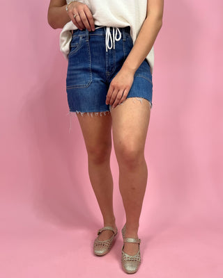 Person wearing a denim skirt on a pink background