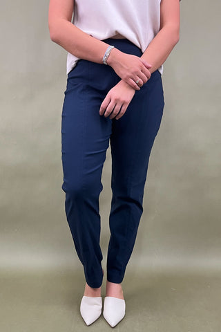 Person wearing navy blue pants and white shoes on a plain background