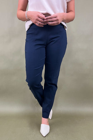 Person wearing navy pants and white shoes on a plain background
