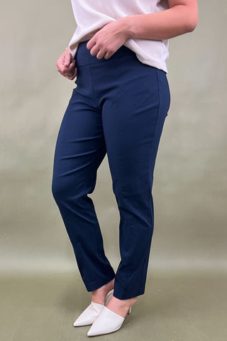 Person wearing navy blue pants and white shoes on a beige background