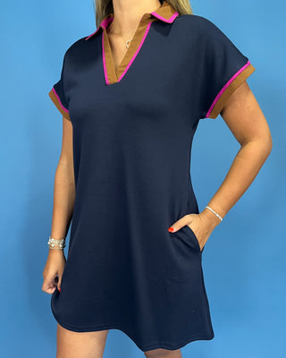 Navy dress with pink trim worn by a person on a blue background