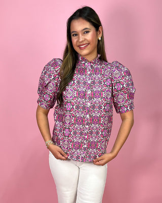 Woman wearing a patterned blouse against a pink background