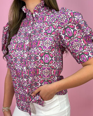 Person wearing a patterned shirt with a pink background