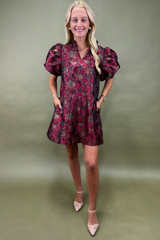 Woman wearing a burgundy floral dress against a green background