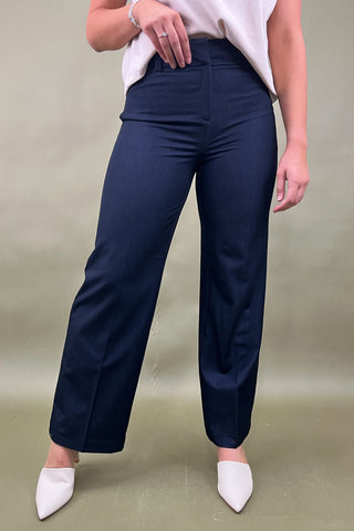 Person wearing navy pants and white shoes on a plain background