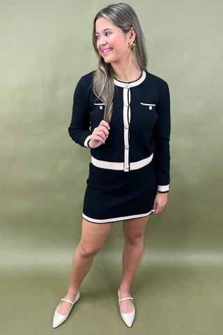 Woman wearing a black and white outfit against a green background