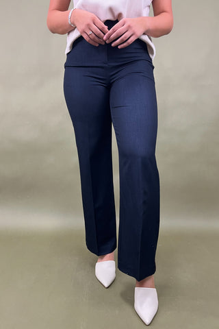 Person wearing navy blue pants and white shoes on a beige background