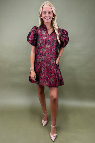 Woman wearing a red floral dress against a green background