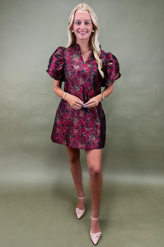 Woman wearing a floral dress against a plain background
