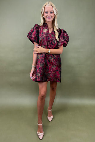Woman wearing a patterned dress against a green background
