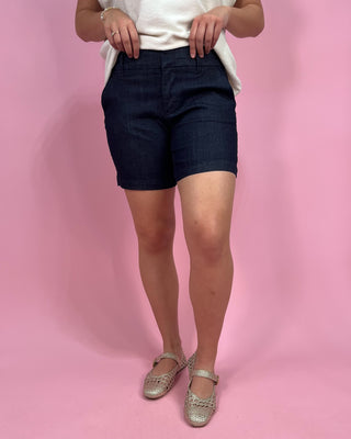 Person wearing navy shorts on a pink background