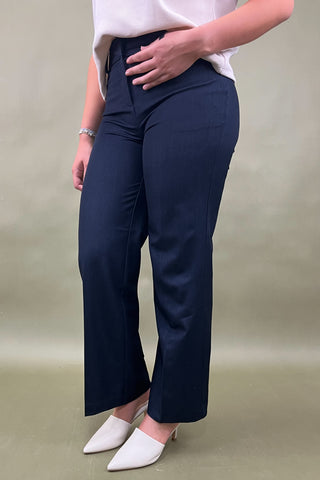 Person wearing navy pants and white shoes on a beige background