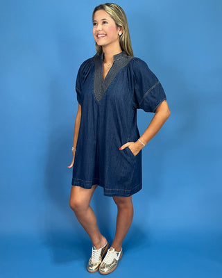 Blue denim dress with embroidered details on a blue background
