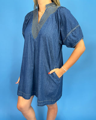 Woman wearing a blue denim dress against a blue background