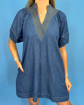 Blue denim dress with embroidered details on a blue background