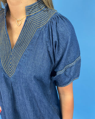Blue denim dress with yellow stitching on a blue background