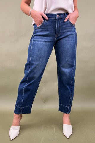 Person wearing blue jeans and white shoes on a plain background