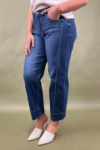 Person wearing blue jeans and white shoes on a plain background