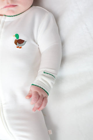 Baby wearing a white long-sleeve shirt with a duck design on a white background