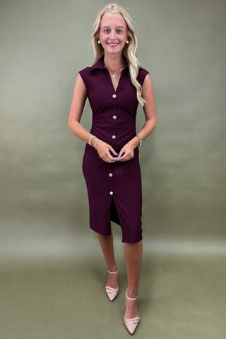 Woman wearing a purple dress with white buttons against a green background