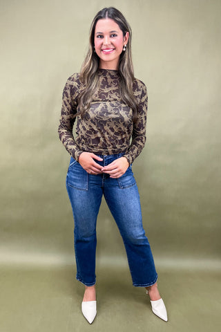 Woman wearing a leopard print top and blue jeans against a green background
