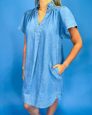 Woman wearing a blue denim dress against a blue background