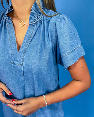 Person wearing a blue denim dress against a blue background