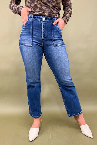 Person wearing blue jeans and a camouflage top on a beige background