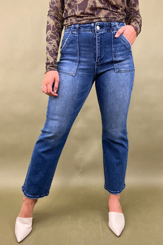 Person wearing blue jeans and a patterned top on a beige background