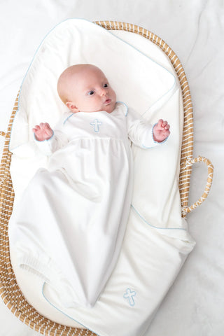 Newborn baby wrapped in a white swaddle blanket lying in a woven basket.