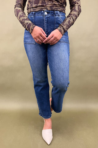 Person wearing blue jeans and a patterned top on a beige background