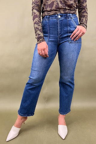 Person wearing blue jeans and a camouflage top on a beige background