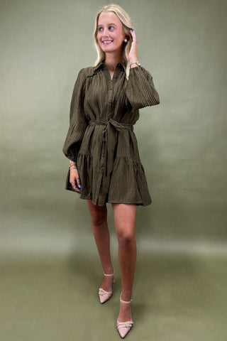 Woman wearing an olive green dress against a matching background