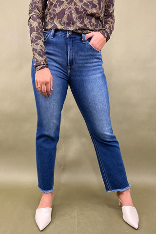 Person wearing blue jeans and a patterned top on a beige background