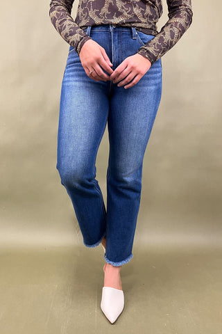 Person wearing blue jeans and a patterned top on a beige background