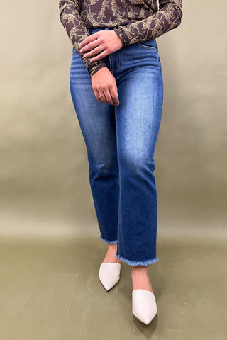 Person wearing blue jeans and a patterned top on a beige background