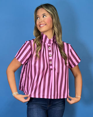 Pink and burgundy vertical striped short sleeve top with a high neckline, pleated front, and decorative gold button details.
