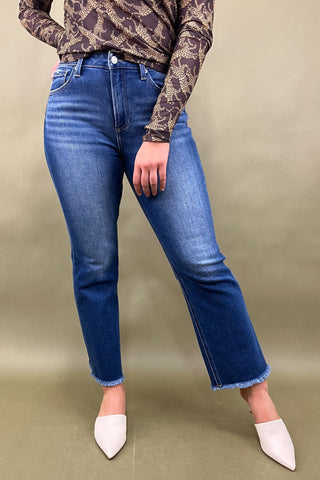 Person wearing blue jeans and a patterned top on a beige background