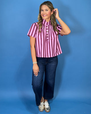 Pink and burgundy vertical striped short sleeve top with a high neckline, pleated front, and decorative gold button details.