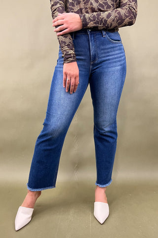 Person wearing blue jeans and a patterned top on a beige background
