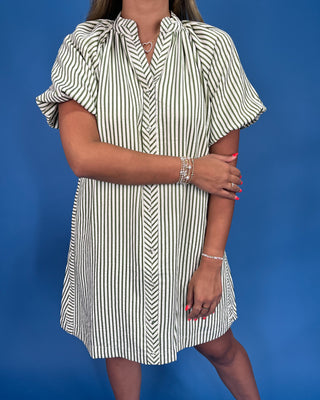 Woman wearing a black and white striped dress against a blue background