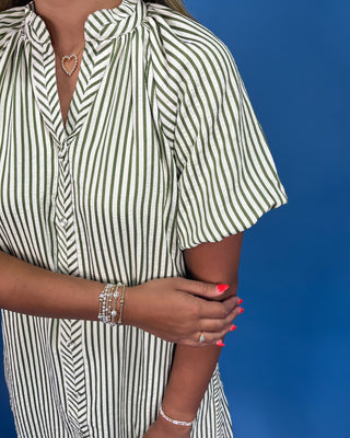 Person wearing a green and white striped dress against a blue background