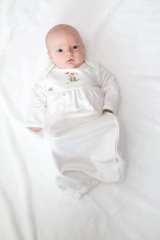 Newborn baby wrapped in a white swaddle with floral patterns on a white background
